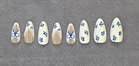 Blue floral and lace press-on nails set with cream and nude base on gray background