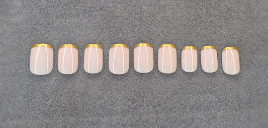 Set of pink press on nails with gold tips and white vertical lines on grey background