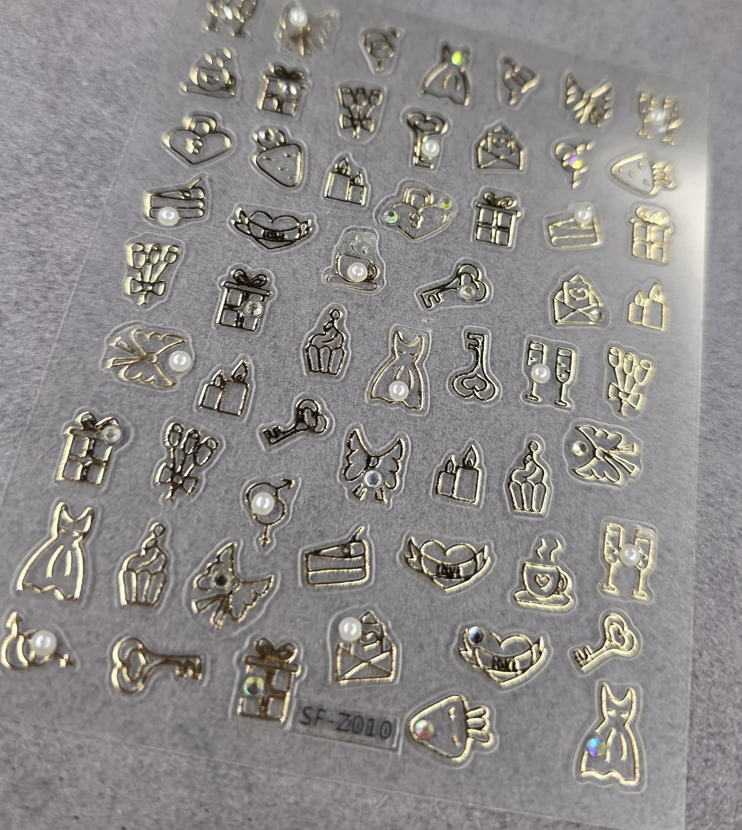 Sheet of metallic gold nail art stickers with hearts, gifts, dresses, and embellishments