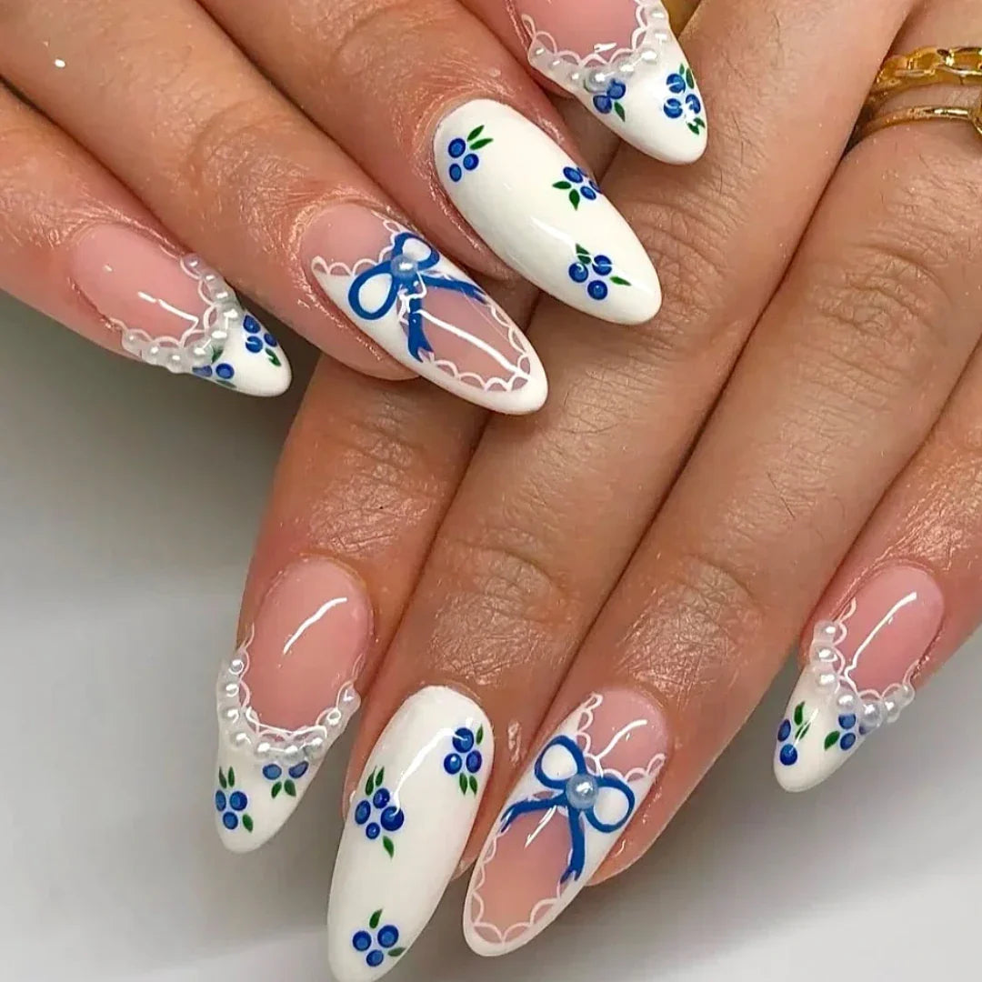 Almond-shaped nails with blue floral lace nail art and delicate white bow accents