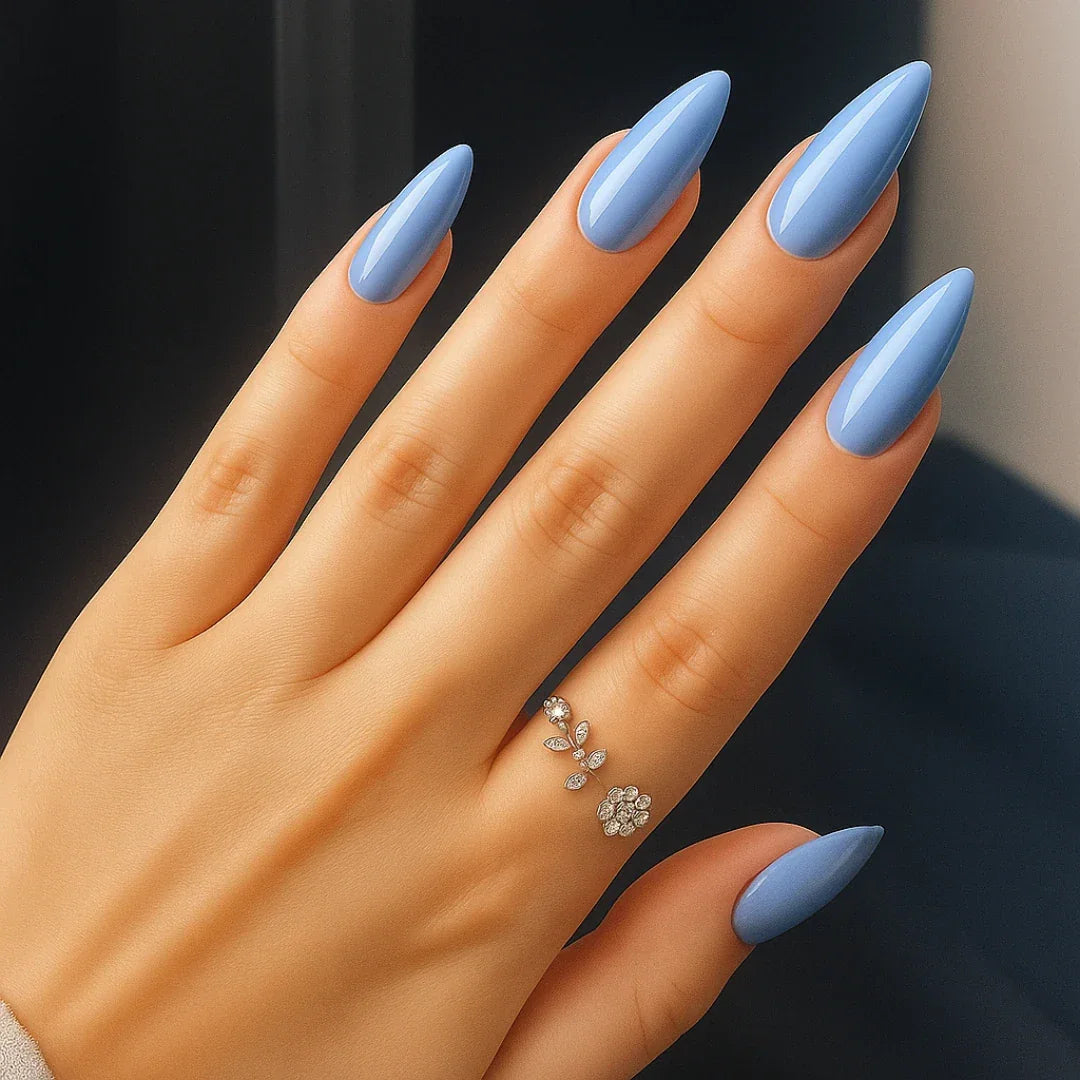 Hand with glossy blue almond shaped press-on nails and a delicate silver ring