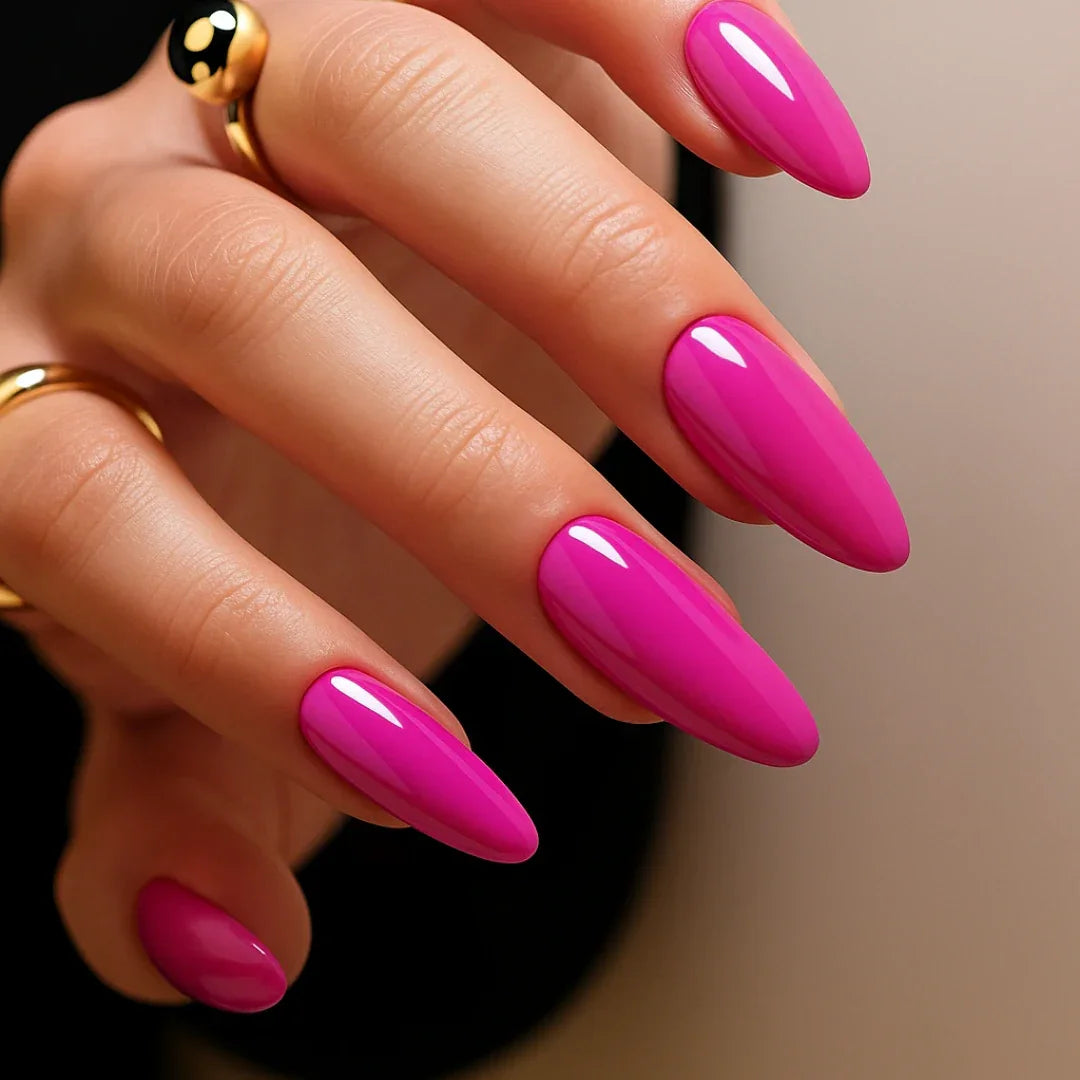 Hand with glossy bold pink almond-shaped nails and gold rings