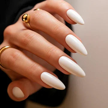 Hand with long classic white almond-shaped nails and gold rings, close-up manicure