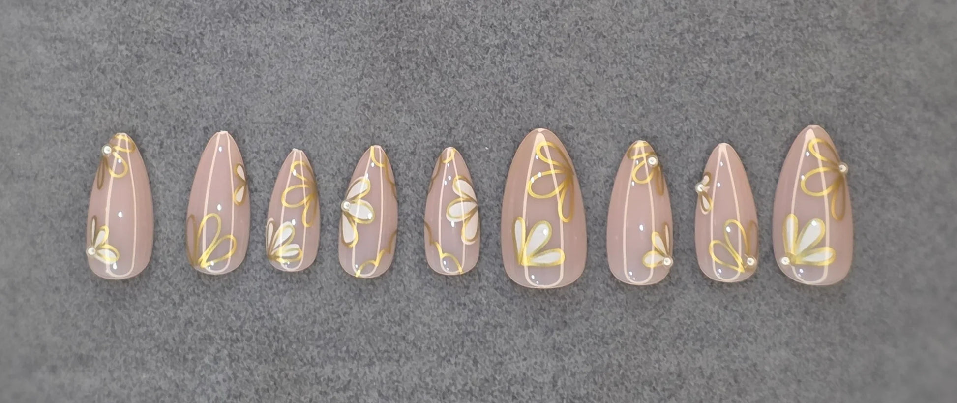 Glossy nude press-on nails with gold and white daisy floral French tip design