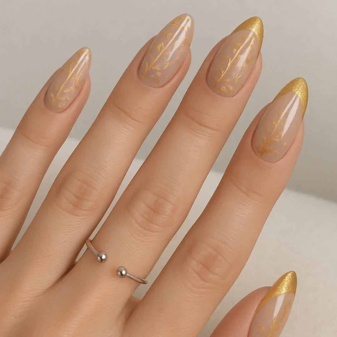 Hand with almond-shaped nails featuring gold chrome tips and elegant gold nail art designs