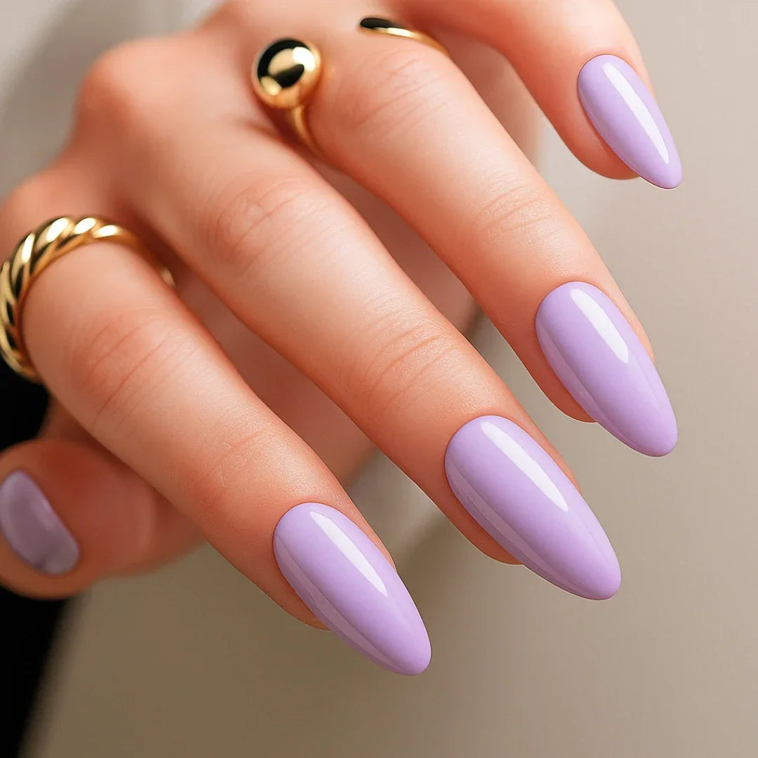 Hand with almond-shaped lavender press-on nails and gold rings