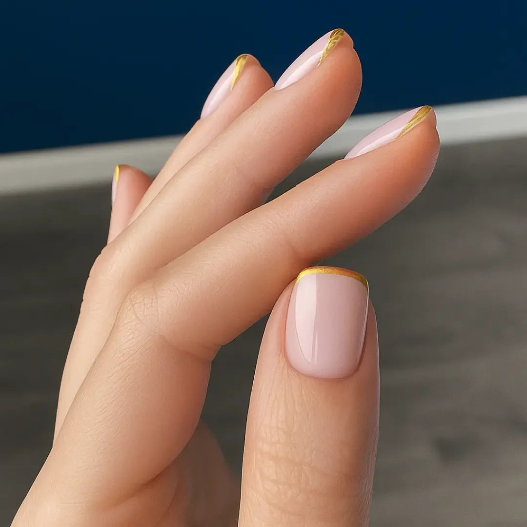 Minimalist gold French tip nails with nude base, modern manicure close-up
