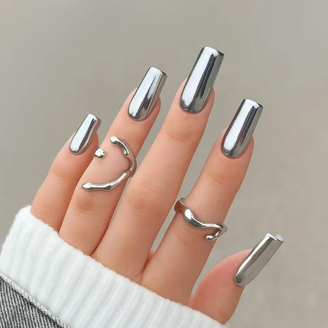 Hand with long mirror chrome silver nails and minimalist silver rings