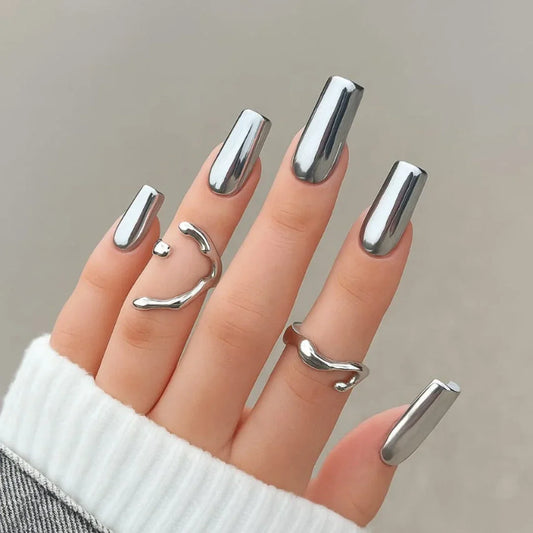 Hand with long mirror chrome silver nails and minimalist silver rings