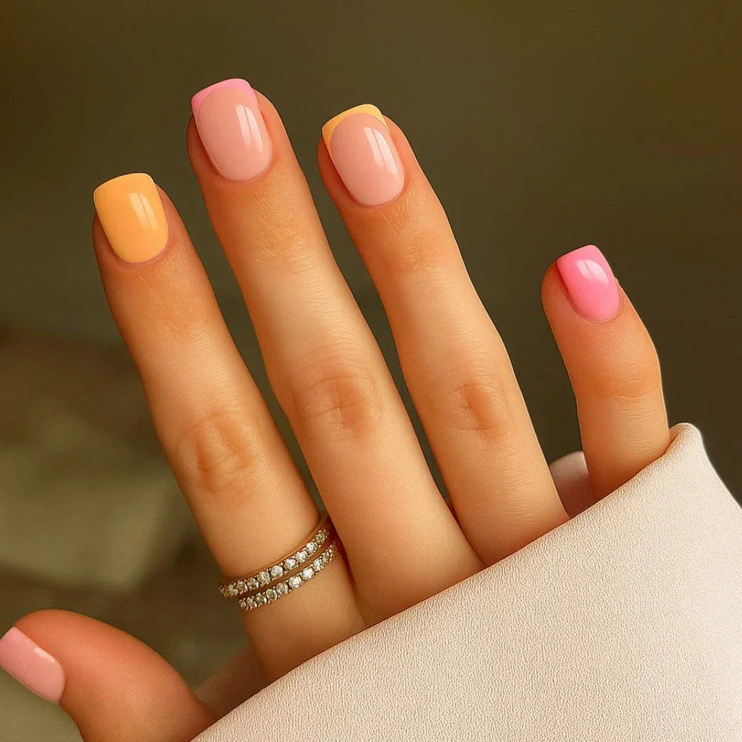 Hand with short square nails featuring peach and pink French tip nail art design