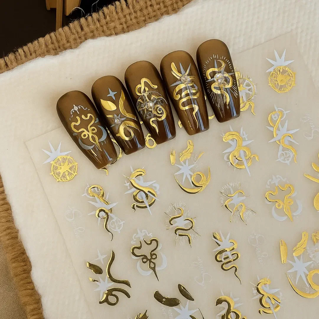 Brown press-on nails with gold and white snake nail art stickers on display sheet