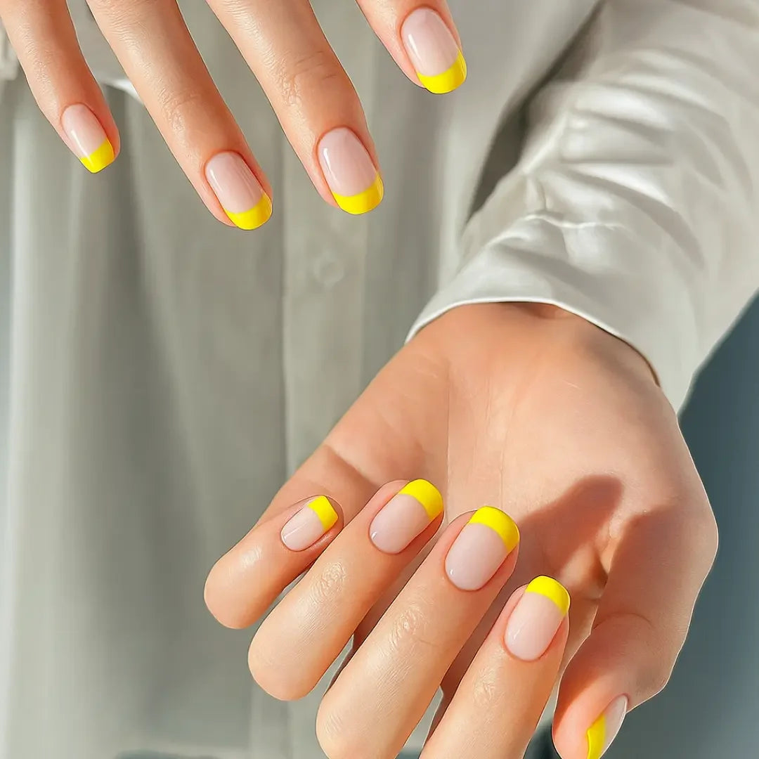 Hands with sunny yellow French tip nails on a neutral background, modern nail design.